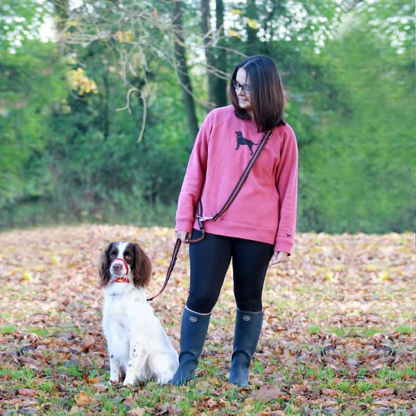 Woman standing in wooded area with spaniel on dog training lead
